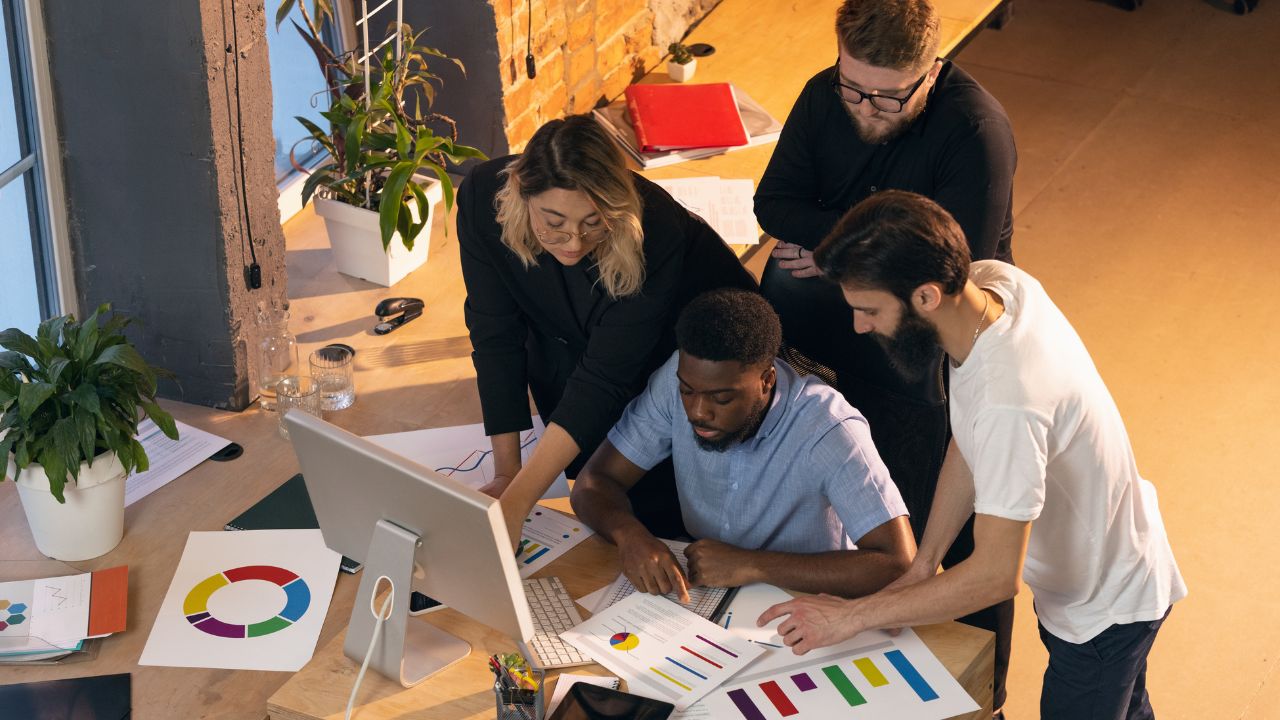 booking plugins for coach websites coworking team gathered around colorful desk collaborating in a group