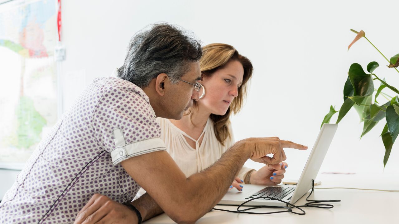 Man and woman looking at a laptop together discussing life coach website design
