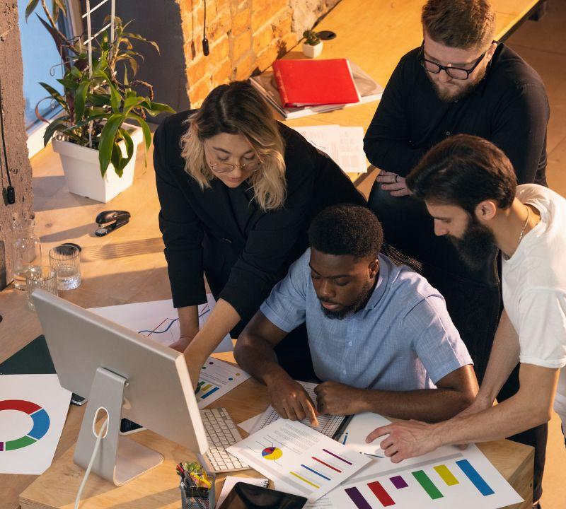 Coworking team gathered around a colorful desk comparing the top booking plugins for coach websites on laptops Coworking team gathered around a colorful desk comparing the top booking plugins for coach websites on laptops