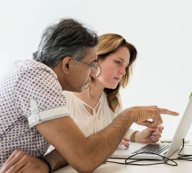 Life coach and web designer reviewing a custom coaching website mockup together on a laptop at a sunlit desk Life coach and web designer reviewing a custom coaching website mockup together on a laptop at a sunlit desk